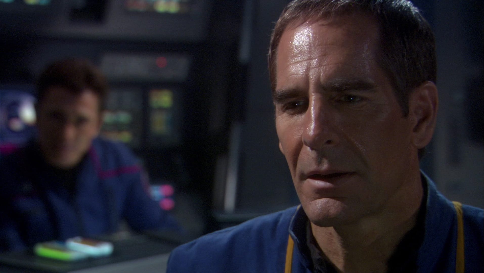 A screenshot (from trekcore) of Scott Bakula as Captain Jonathan Archer, standing on the bridge of his Enterprise. He's a White man with short brown hair and a notably furrowed brow. He looks like he's reaslising something; his eyes are somewhat downcast and unfocused and his lips are slightly parted, suggesting the lower part of his face is more relaxed. The focus is very much on Archer's face -- there is another person in the backgroud, on the left of the image. It's Malcolm Reid (Dominic Keating) but you wouldn't be able to identify him very easily if you didn't already know that it's him.